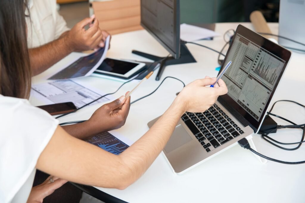 blog-02 Professionals analyzing data charts on a laptop in an office setting, collaboratively discussing insights.